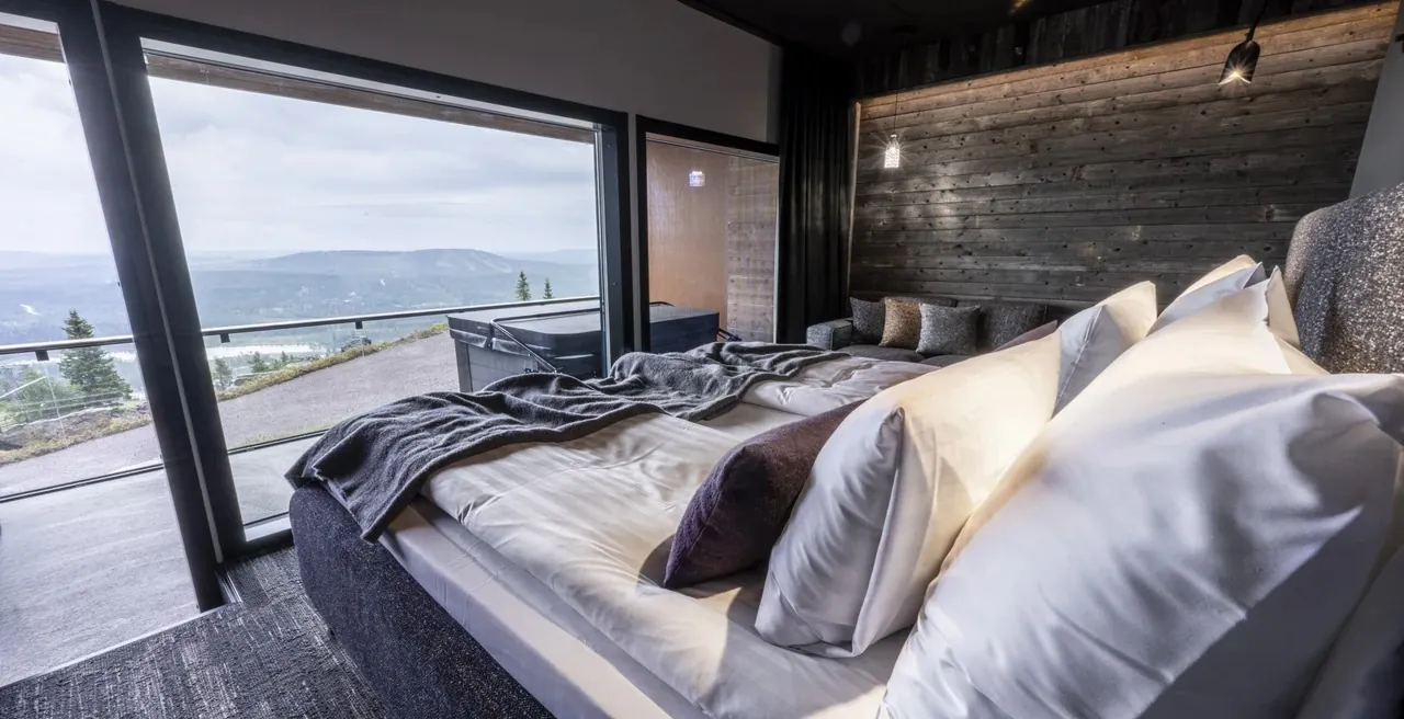 Aurora View Suite Double bed beside wide glazing towards the fell landscape and northern sky